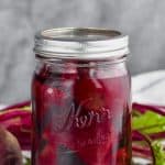 mason jar on a white surface against a gray background filled with pickled beets recipe