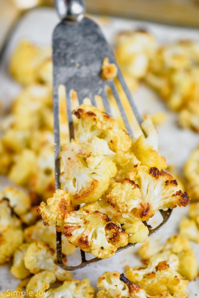 close up of oven roasted cauliflower on a slotted spatula, being dished up