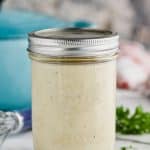 mason jar full of condensed cream of chicken soup on a white counter with a teal pot behind and small bits of parsley off to the right