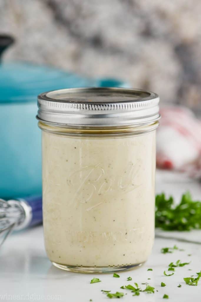 mason jar full of condensed cream of chicken soup on a white counter with a teal pot behind and small bits of parsley off to the right