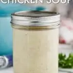 mason jar full of condensed cream of chicken soup on a white counter with a teal pot behind and small bits of parsley off to the right