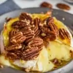 close up picture of baked brie recipe made with honey, pecans, and marmalade