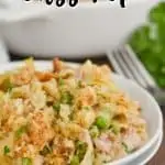 two white plates stacked with a heaping serving of tuna casserole recipe on top and the dish in the background