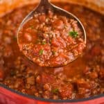 red dutch oven with meat sauce being ladled out, garnished with a little parsley - 19