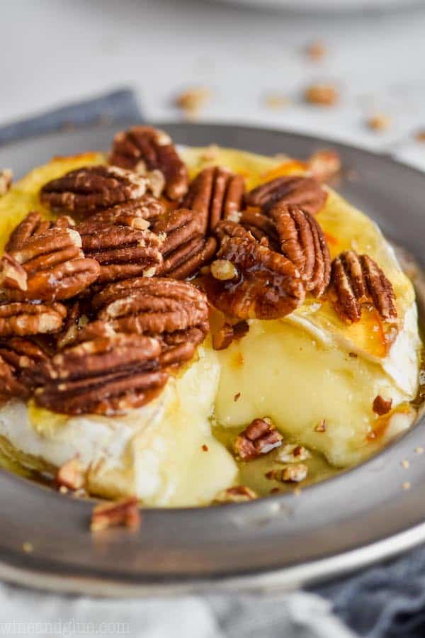 close up picture of baked brie recipe made with honey, pecans, and marmalade