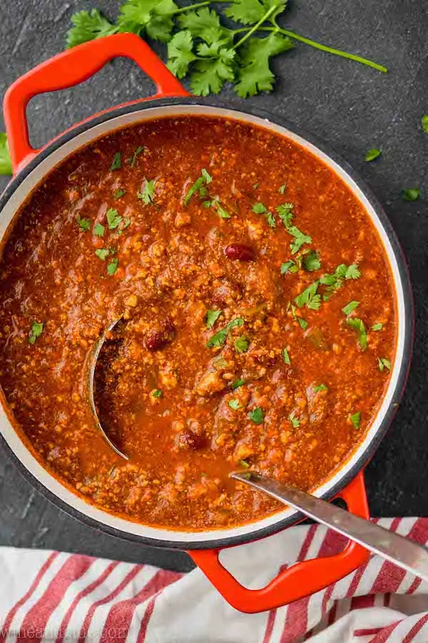 overhead view of a red stock pot with a vegetarian chili recipe and a metal ladle coming out of it