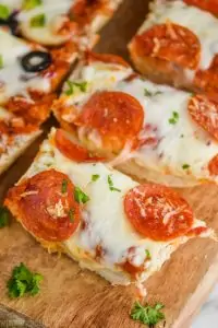 up close of a sliced piece of french bread pizza on a cutting board topped with pepperoni