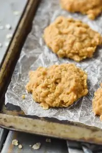 close up of a no bake peanut butter oatmeal cookie on crinkled wax paper on a old baking sheet