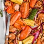overhead view of a spoon in a pan of sausage, beans and roasted vegetables to make a sheet pan dinner