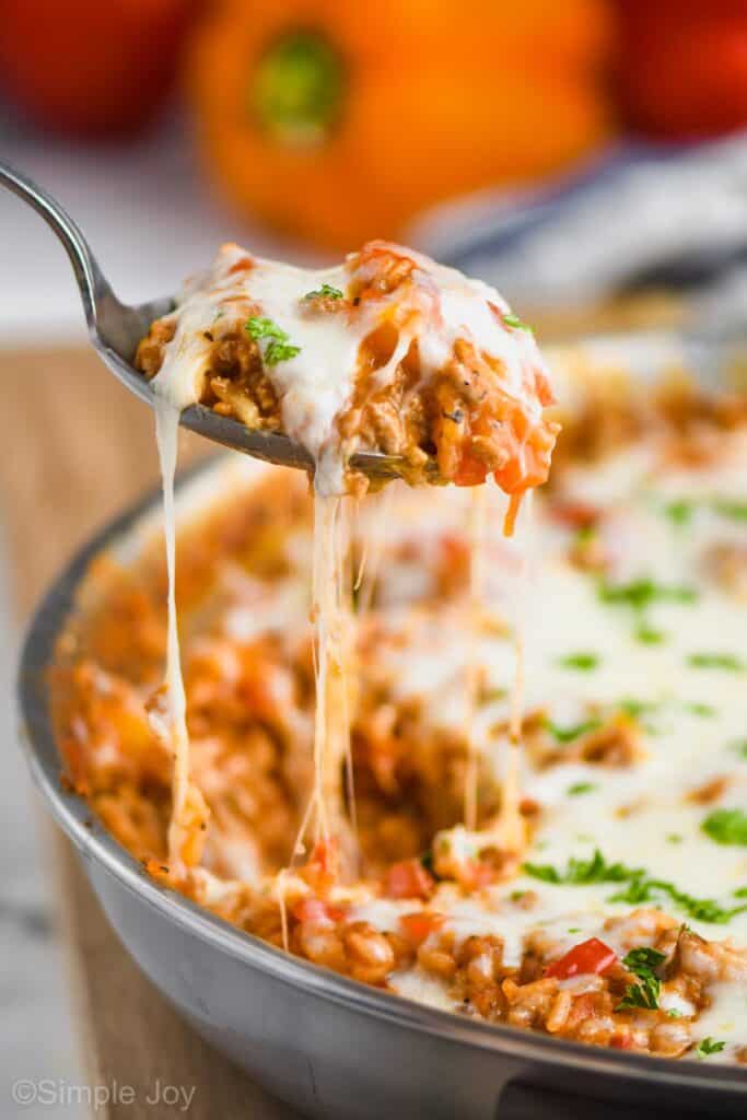 a spoonful of cheesy stuffed pepper casserole lifting out of the skillet