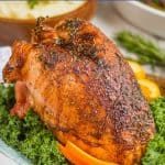 a cooked turkey breast from the best turkey breast recipe sitting on a platter with greens and orange slices under it