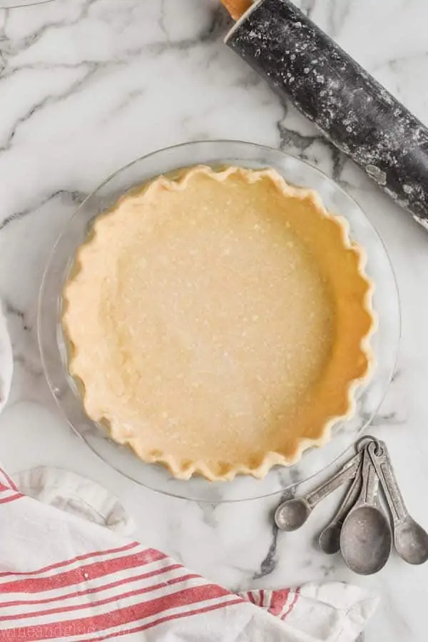 a pie crust recipe that has been transferred to a glass pie pan and the rim of it has been pinched