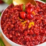 up close picture of a white bowl full of cranberry relish being spooned up by a golden spoon - 31