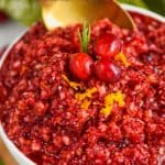 up close picture of a white bowl full of cranberry relish being spooned up by a golden spoon