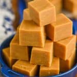 a pyramid of peanut butter fudge piled into a small blue dish with handles on a white napkin and a wood block - 11