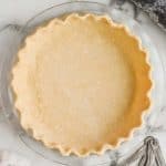 a pie crust recipe that has been transferred to a glass pie pan and the rim of it has been pinched