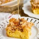 a square piece of French toast casserole on a fancy whit plate with streusel on top, and syrup being poured on - 13