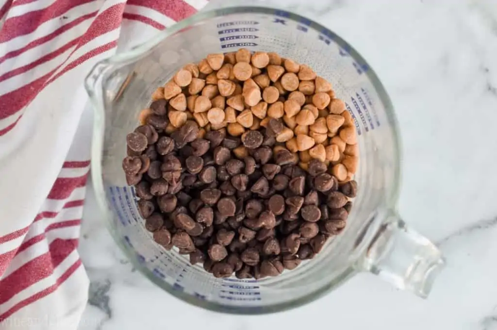 overhead view of a glass measuring cup with chocolate chips and butterscotch chips in it