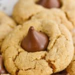 a close up photo of a peanut butter blossom - crisp peanut butter cookie with a Hershey kiss buried into the top
