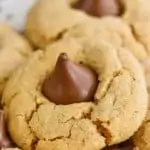 a close up photo of a peanut butter blossom - crisp peanut butter cookie with a Hershey kiss buried into the top