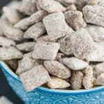 a blue detailed bowl against a dark surface overflowing with a puppy chow recipe