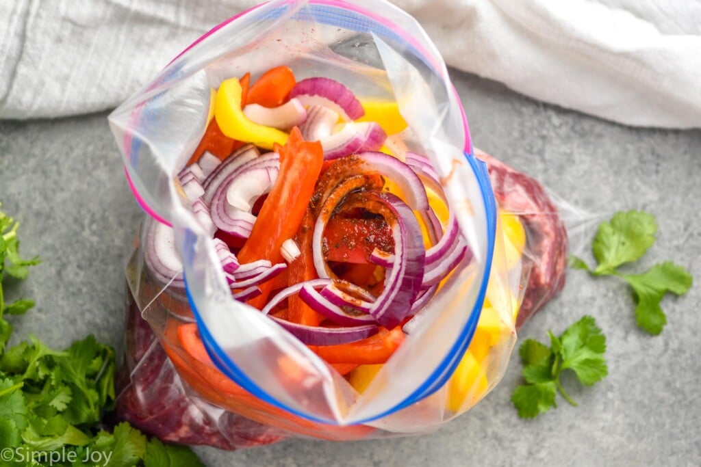 Overhead photo of vegetables and marinade in a bag for Steak Fajitas recipe.