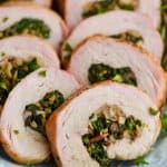 a close up of a piece of stuffed pork loin that has been cooked and sliced, with mushrooms and spinach in the middle