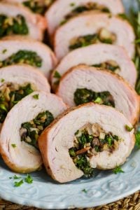 a close up of a piece of stuffed pork loin that has been cooked and sliced, with mushrooms and spinach in the middle