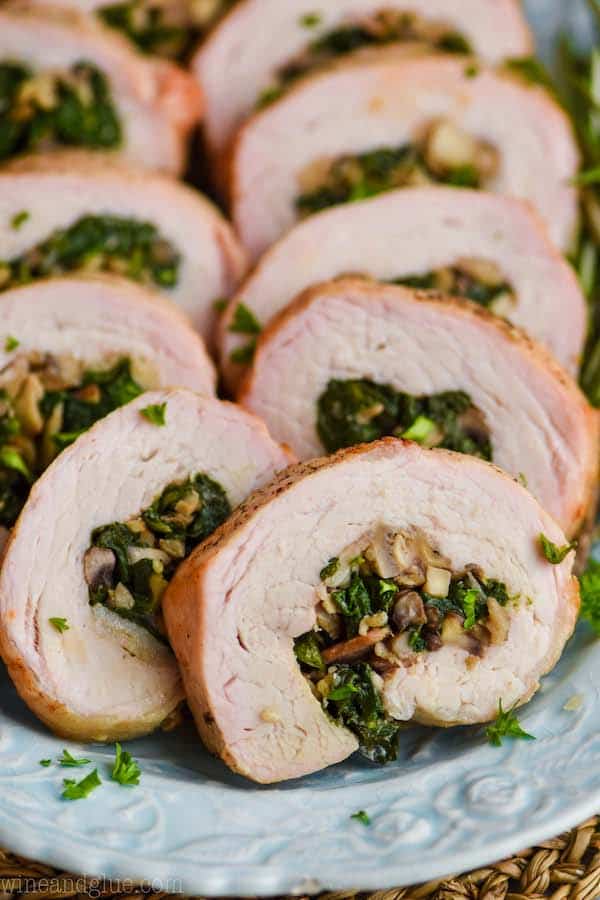 a close up of a piece of stuffed pork loin that has been cooked and sliced, with mushrooms and spinach in the middle