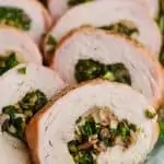 a close up of a piece of stuffed pork loin that has been cooked and sliced, with mushrooms and spinach in the middle