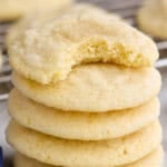 a stack of five sugar cookies with a bite missing out of the top one
