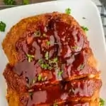 overhead view of a turkey meatloaf on a white plate that has been sliced a little and topped with fresh parsley