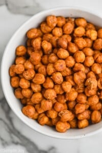 overhead view of a white bowl on a marble countertop full of roasted chickpeas - 11
