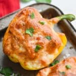 a half yellow bell pepper that is a chicken fajita stuffed pepper topped with bubbly brown cheese on an old baking sheet and garnished with cilantro - 9