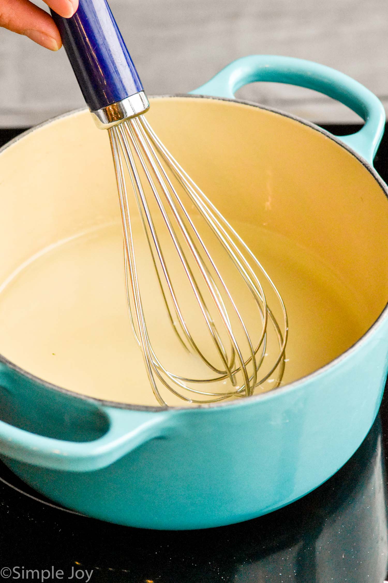 a whisk in a small sauce pan making simple syrup