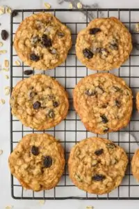 overhead view of six oatmeal raisin cookies on a wire cooling rack on a marble countertop