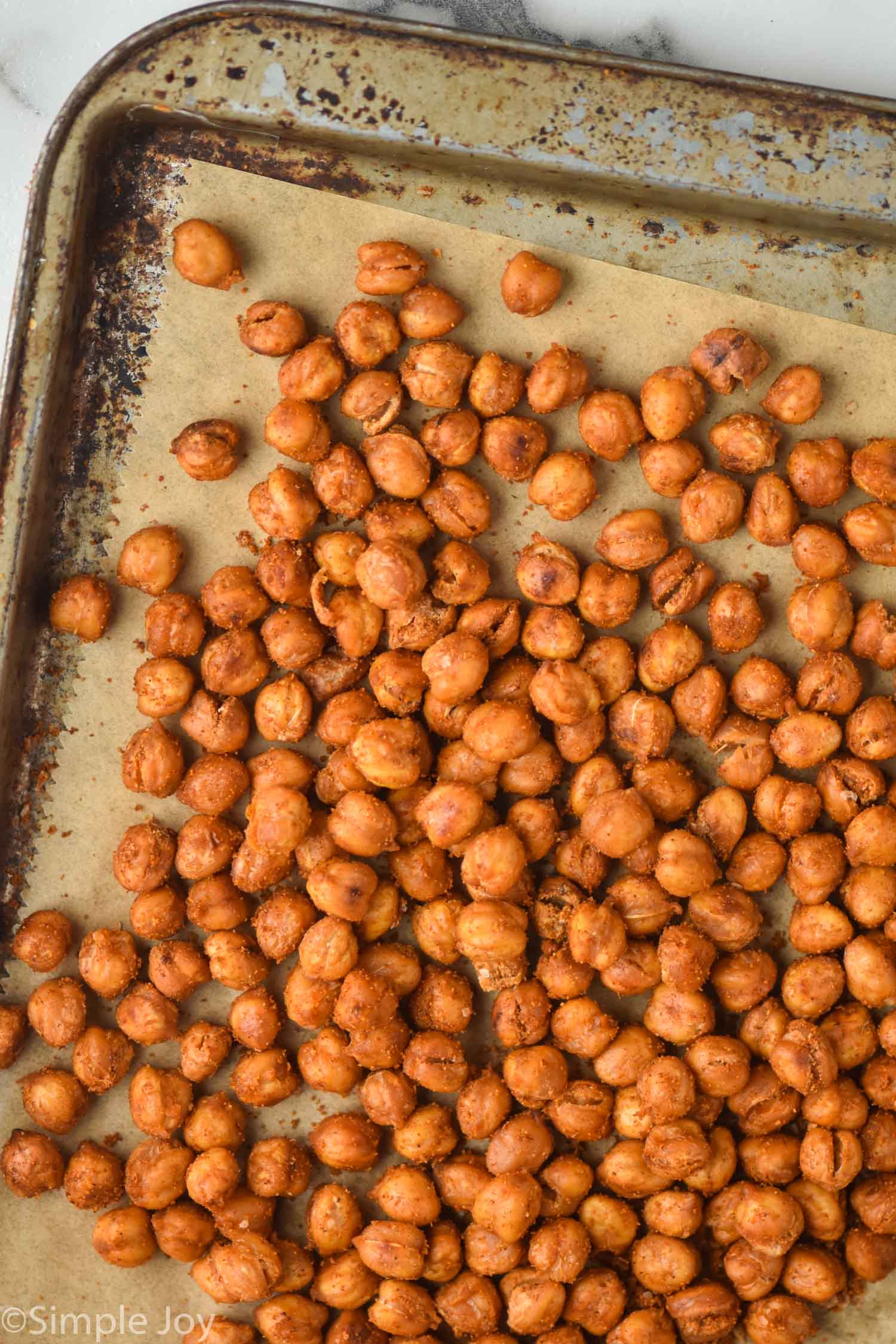 overhead view of roasted chickpeas on a vintage tray that is lined with parchment paper