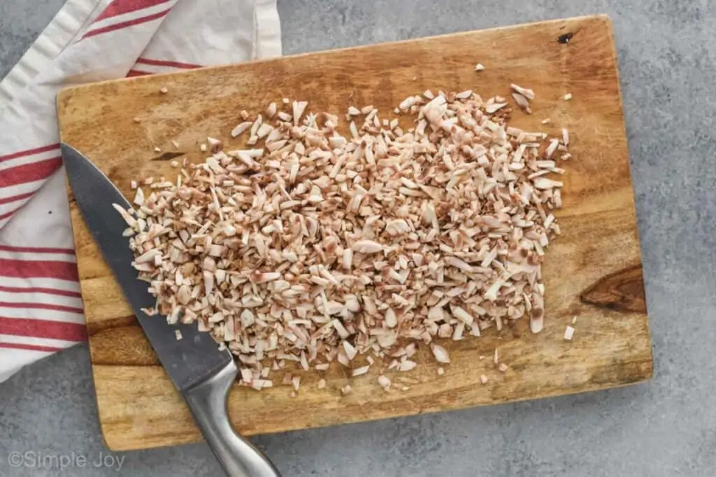 an overhead view of a pile of mushrooms on a cutting board that have been diced very small