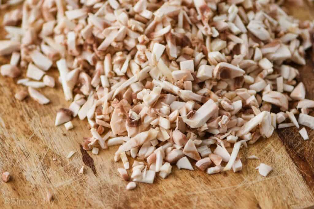 a close up picture of a pile of very finely diced mushrooms on a cutting board