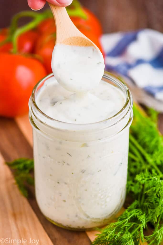 small wooden spoon lifting out of a mason jar of ranch dressing