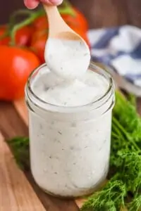 small wooden spoon lifting out of a mason jar of ranch dressing