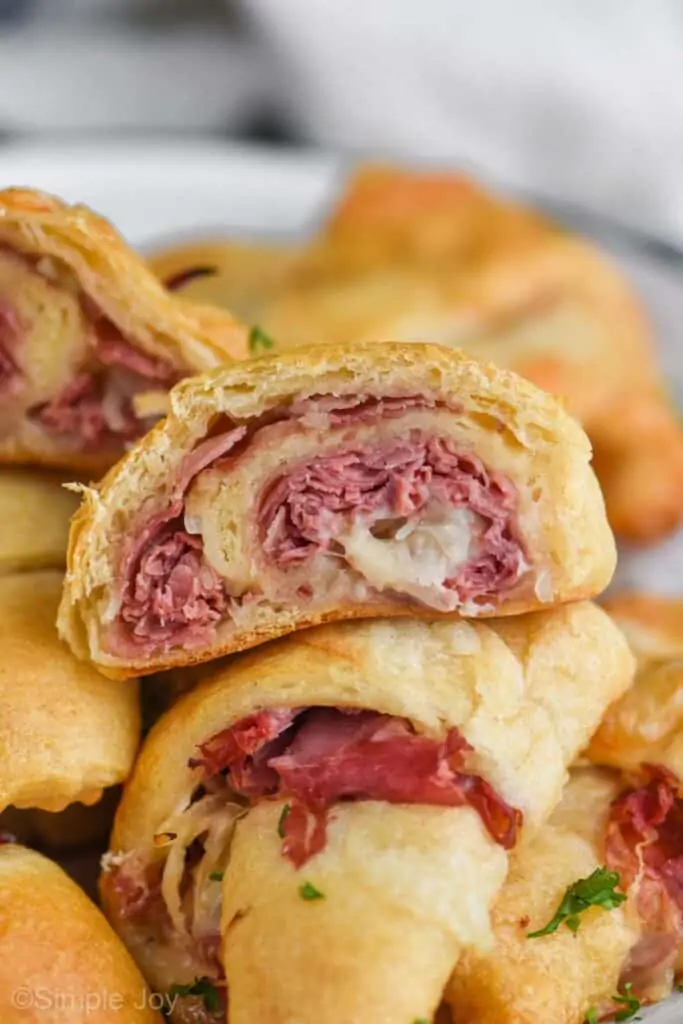 close up of a reuben crescent roll cut in half, you can see corned beef and melted Swiss cheese