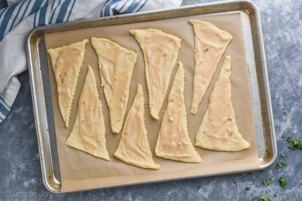 overhead of a baking sheet with 8 crescent roll triangles rolled out with thousand island dressing