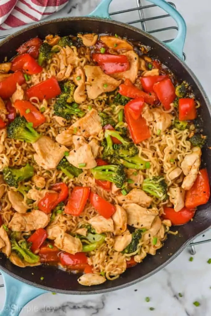 up close overhead view of a stir fry noodle recipe in a teal skillet with ramen noodles, chicken, and vegetables