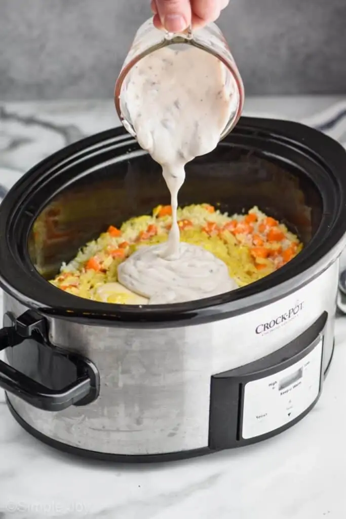 condensed cream of mushroom soup being poured into chicken and rice casserole