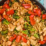 up close overhead view of a stir fry noodle recipe in a teal skillet with ramen noodles, chicken, and vegetables