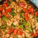 up close overhead view of a stir fry noodle recipe in a teal skillet with ramen noodles, chicken, and vegetables