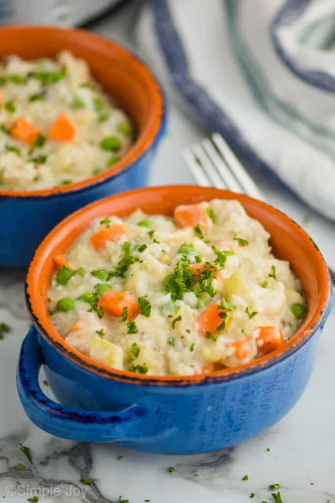 close up of chicken and rice casserole garnished with fresh parsley in a small blue ceramic soup bowl