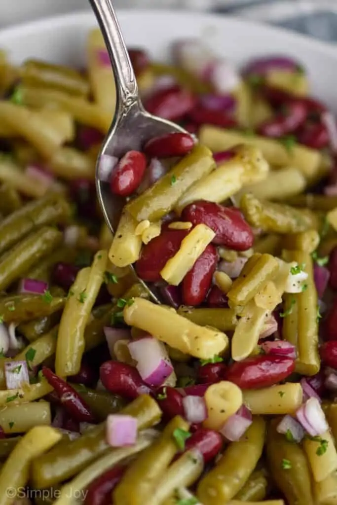 A close up photo of the bean salad being mixed together with a spoon digging into the salad