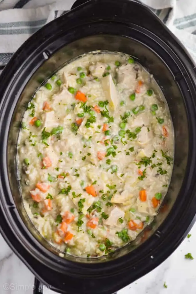 overhead view of a crockpot with chicken and rice casserole garnished with fresh parsley 